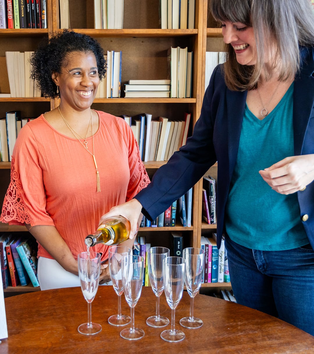 Ghostwriting and publishing expert Amanda Edgar pours champagne for one of Page & Podium's clients in a bookstore.